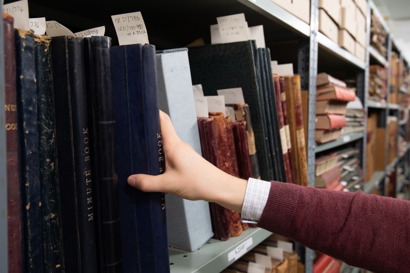 A persons hand taking a book from a bookshelf
