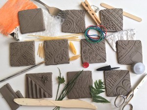 A photo of different designs on squares of wet clay.
