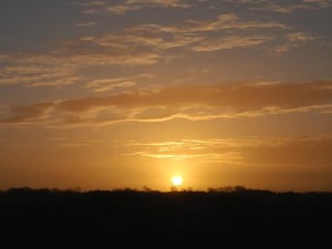 A photo of an orange sunset with some clouds in the sky. 