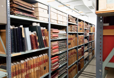 Depicting metal shelves  stacked with many books and archival material on each shelf