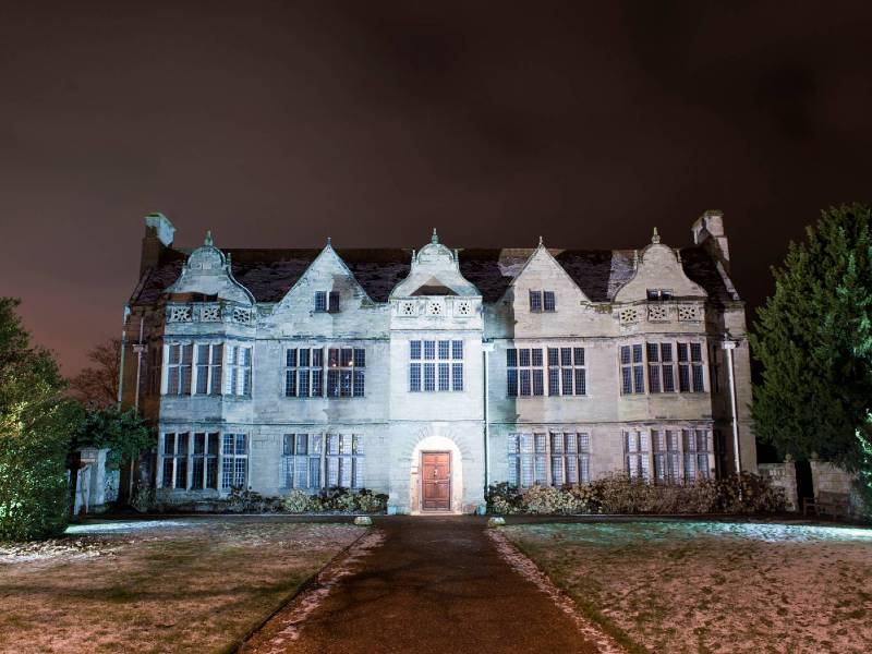 A front view of St John's House at night, being lit up with colourful lights