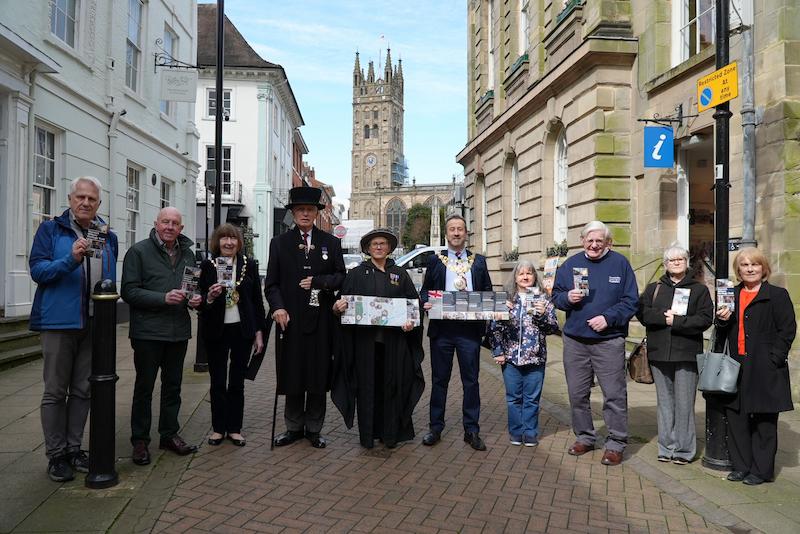 A group of people associated with the military in Warwickshire holding pamphlets highlighting the walk route