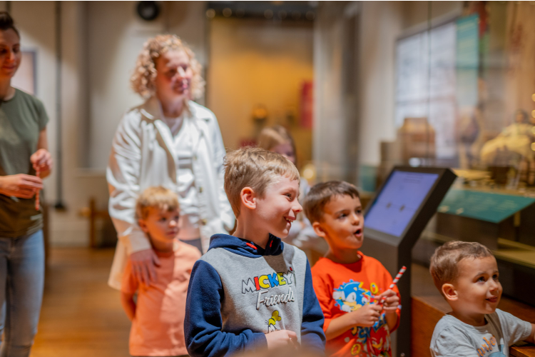 Four children stood infront of parents looking at an interactive exhibit.