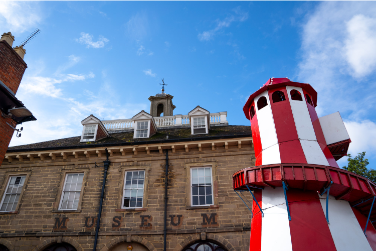 Red and white striped helter-skelter infront of teh Market Hall Museum with blue skies behind.